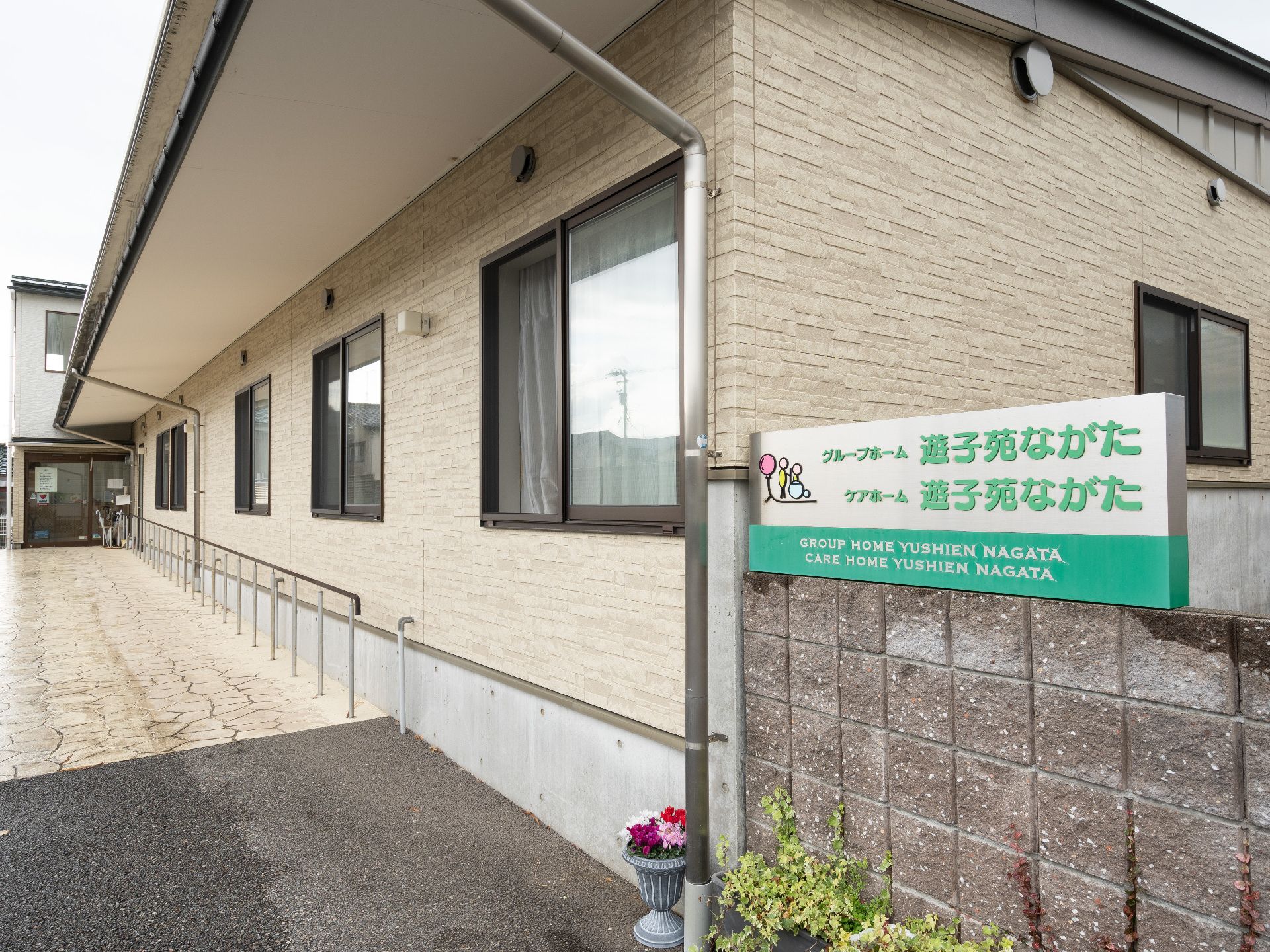 車椅子に座っている高齢女性と隣で寄り添う男性ヘルパー