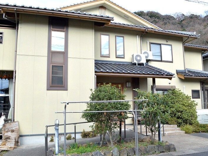 ベージュ系の外壁の2階建ての建物は一般の家庭のような雰囲気で、表札や看板はない。建物の前には洗濯物干し場もある。