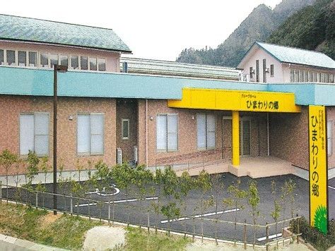 「ひまわりの郷」の看板が掲げられている建物お様子。駐車場スペースがある様子