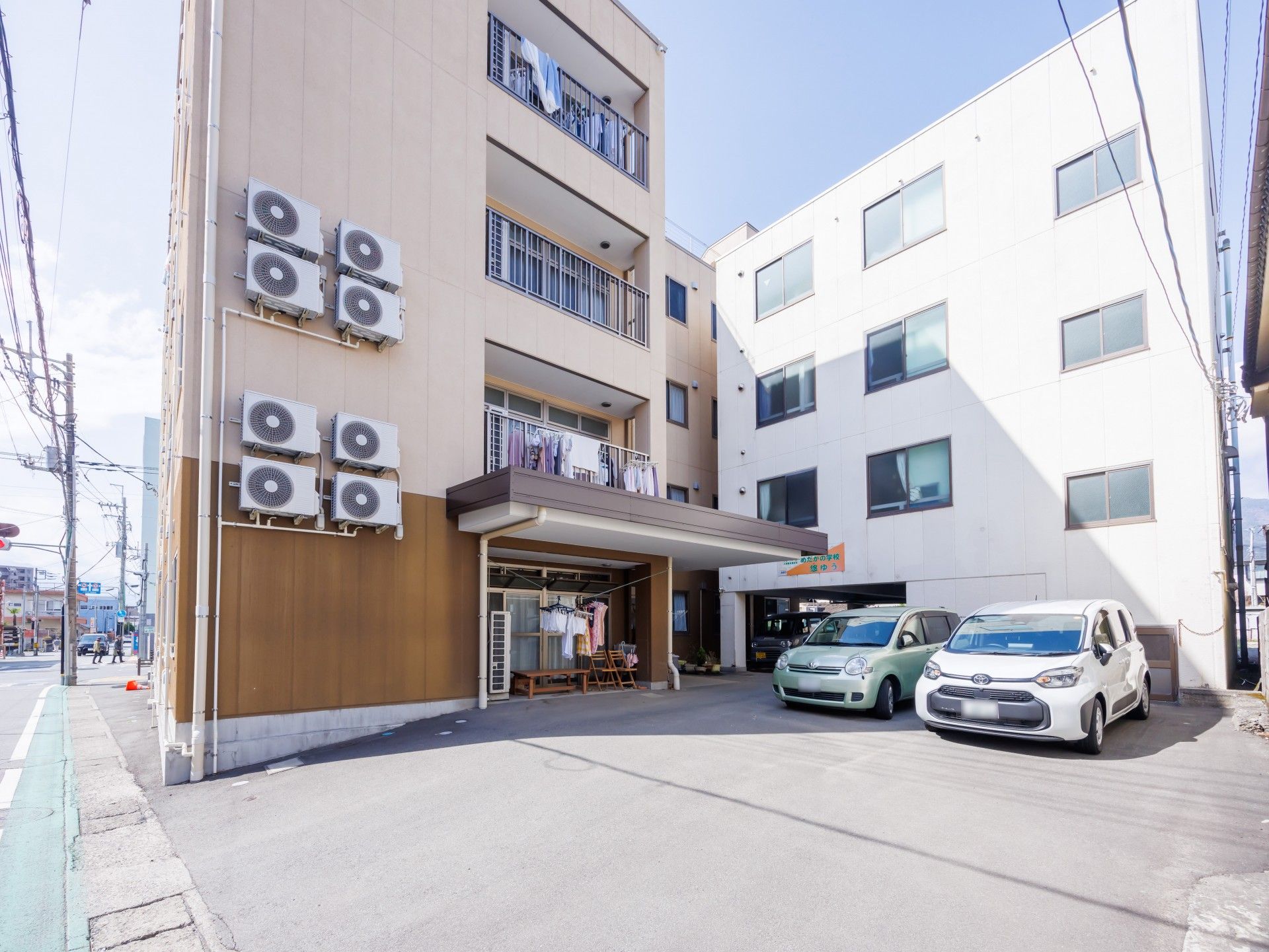 日当たりのいい屋外で散歩をする車いすの高齢女性とエプロンを付けた女性スタッフ。