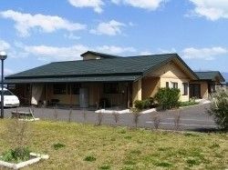 平屋建ての建物。広い駐車スペースもあり、周辺には緑があふれている、
