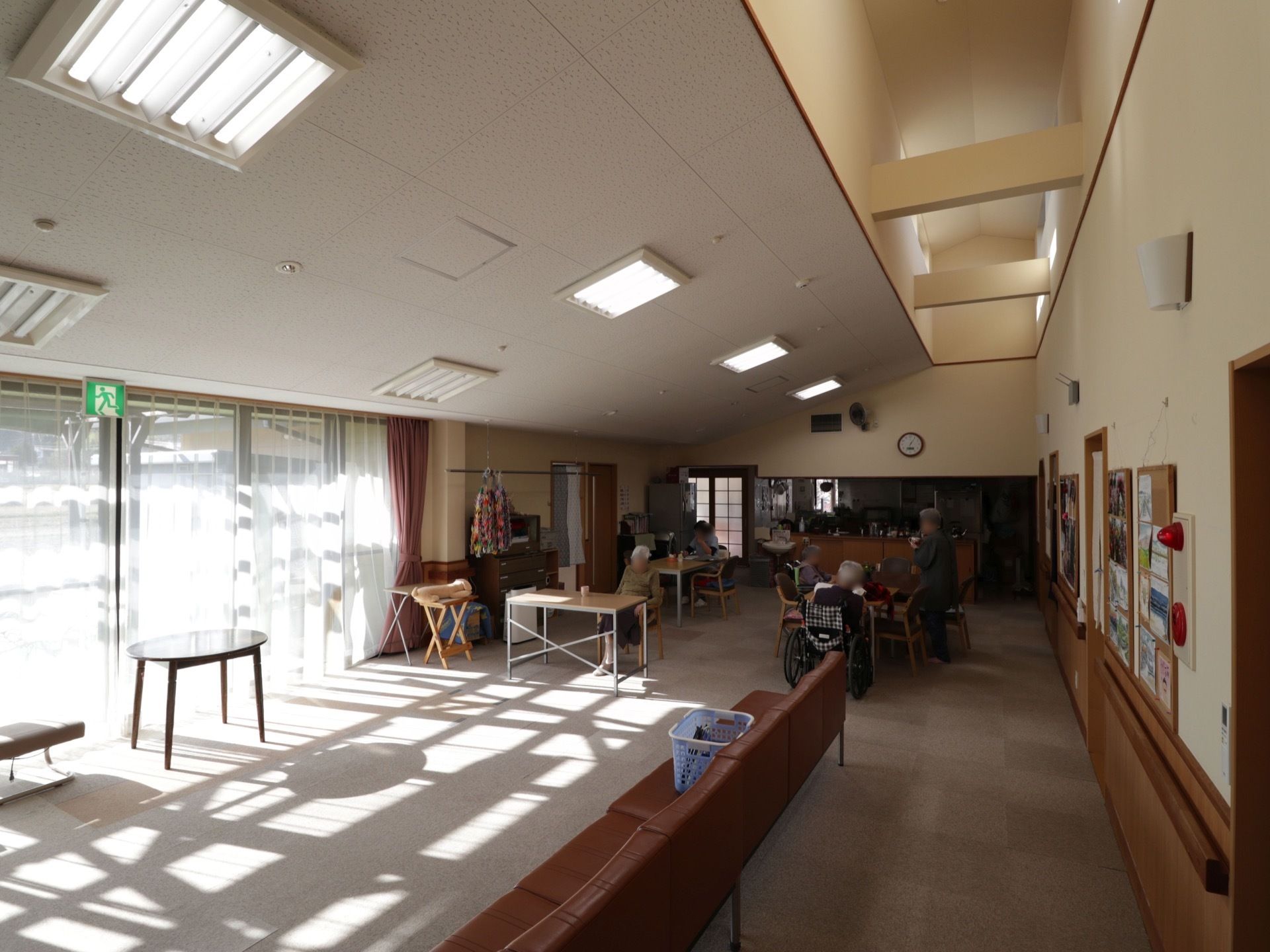 施設内には、広い共有スペースが確保されている。奥にはキッチンがあり、そばに椅子やテーブルがたくさん並べられている。