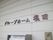 施設の玄関先の白い外壁に、立体的な文字で施設名が書かれている。下には金属製のポストとインターホンが付いている。