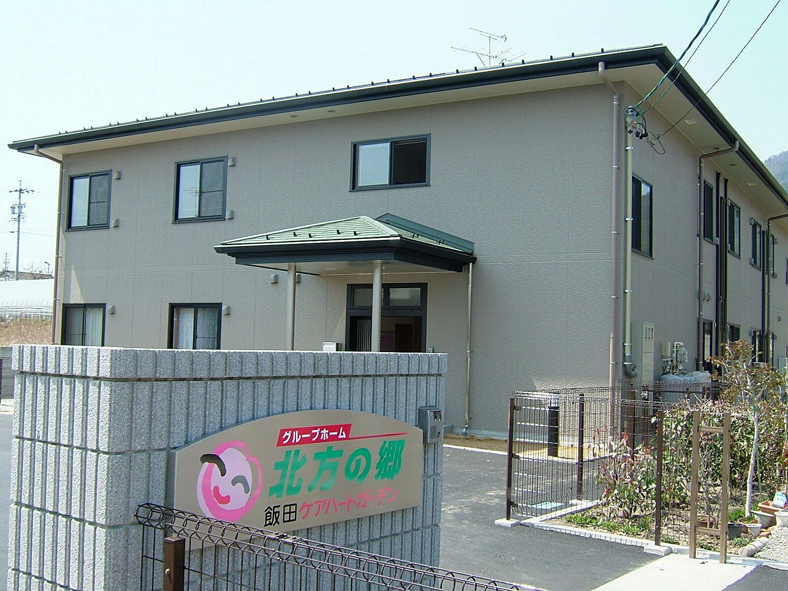 2階建ての建物はブラウン系。玄関に屋根、2階部分にはベランダが付いている。