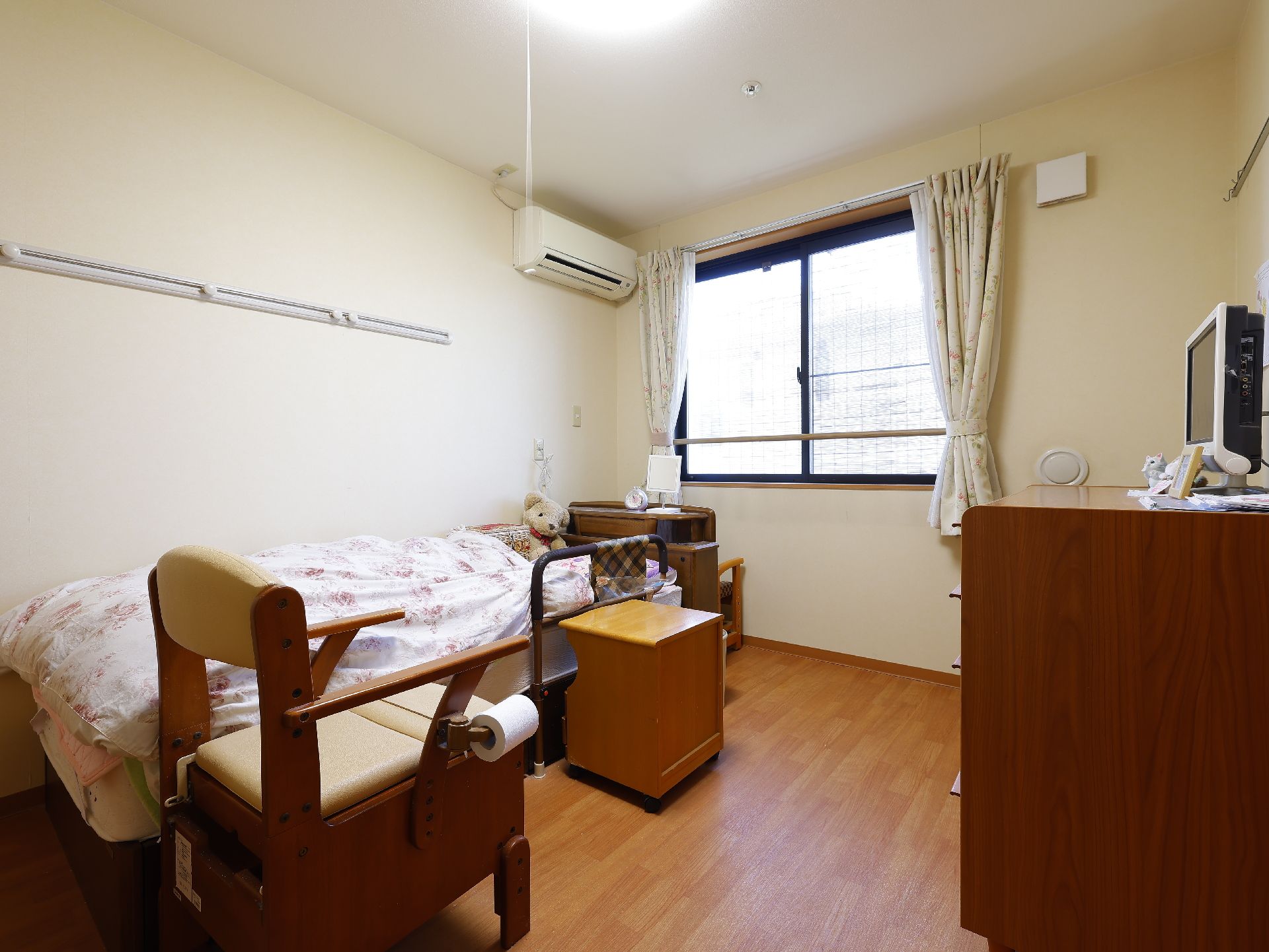 窓から光がたっぷりと入り、介護ベッドや家具類が置かれている居室