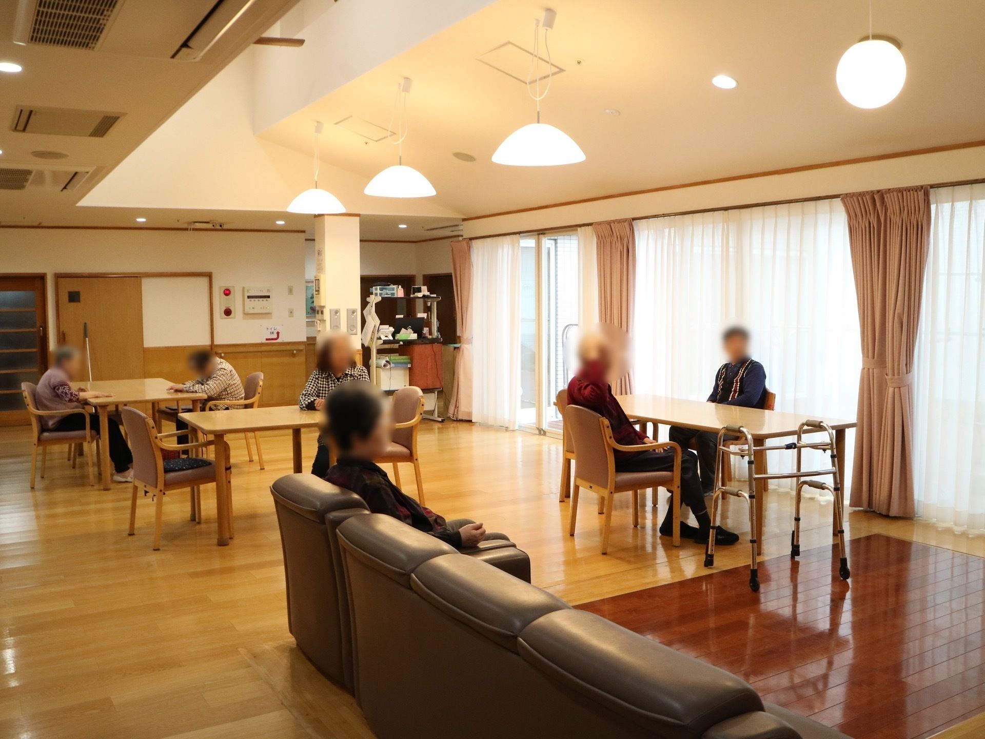 ソファや椅子で入居者がくつろいでいる、温かい雰囲気の共有スペース