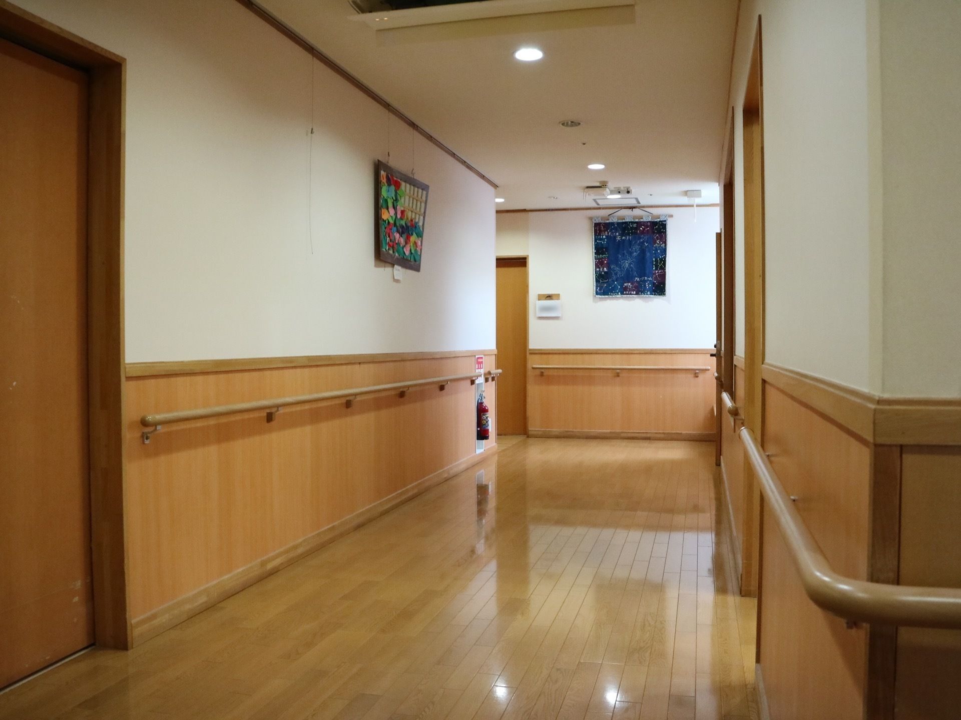 白色と木目調の真新しい通路である。手すりが連続して設置されており、床は周りの風景が映るくらいピカピカである。