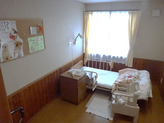 介護用ベッドと椅子、物入などが置いてある施設内の居室の様子