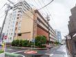 アスファルトの道路沿いに立地しているベージュ系の外観で６階建ての建物