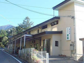 ２階建ての建物は横に長く、玄関の横にはホームの名前が書かれている。自然が多い地域。