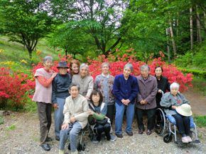 紅葉のきれいな場所で入居者とスタッフがそろって記念撮影。