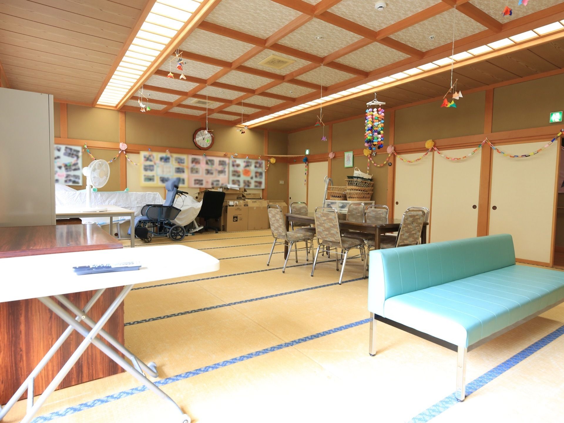 畳敷きの広い部屋には、洋風の椅子とテーブル、少し間隔をおいてブルーの長いソファが用意されている。車椅子も１台壁面近くに置いてある。