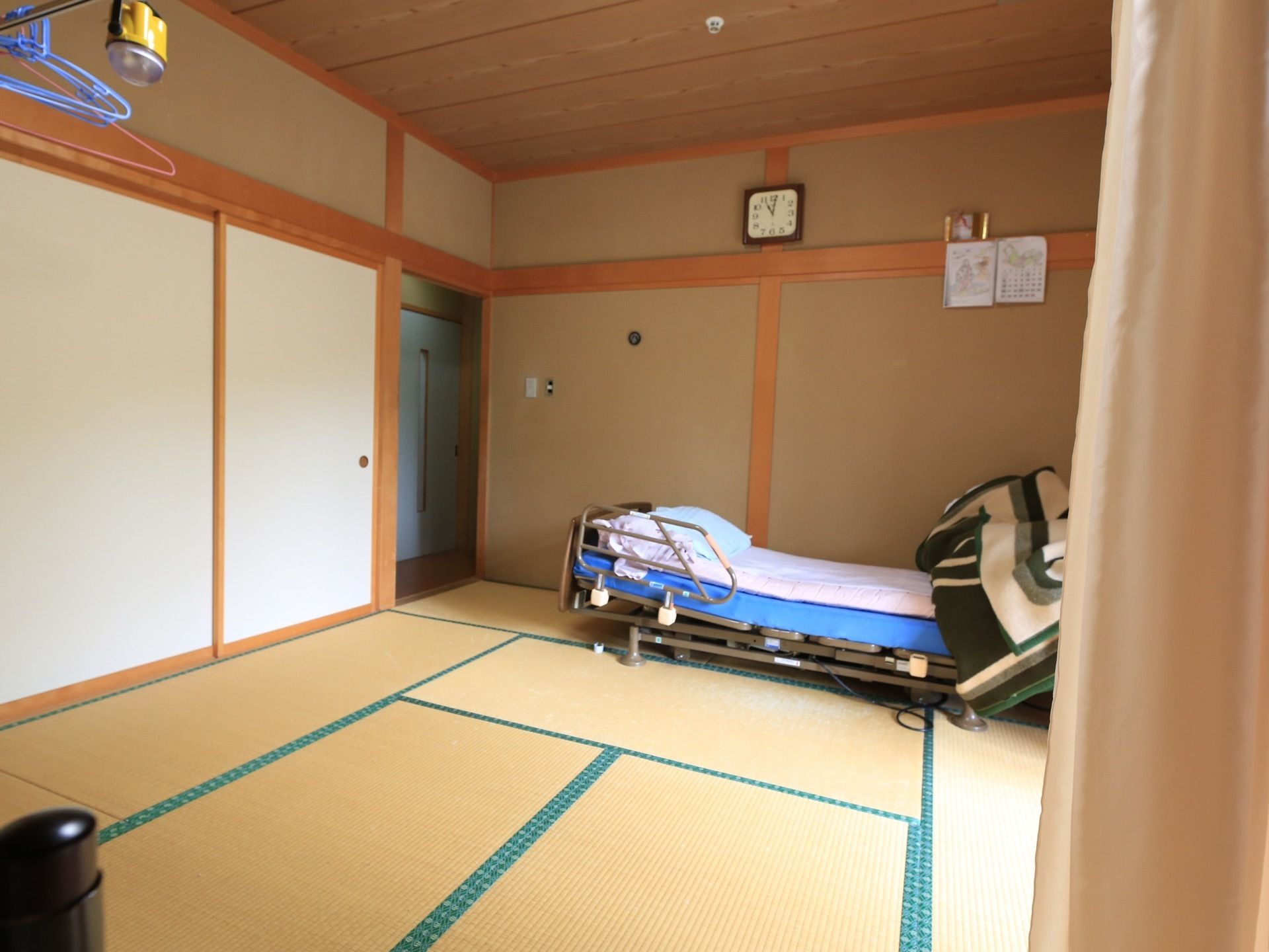 居室は、一般的な畳を敷いた和室である。部屋の壁には時計があり、壁面際には背中の角度と高さが調節できる介護用ベッドが設置されている。