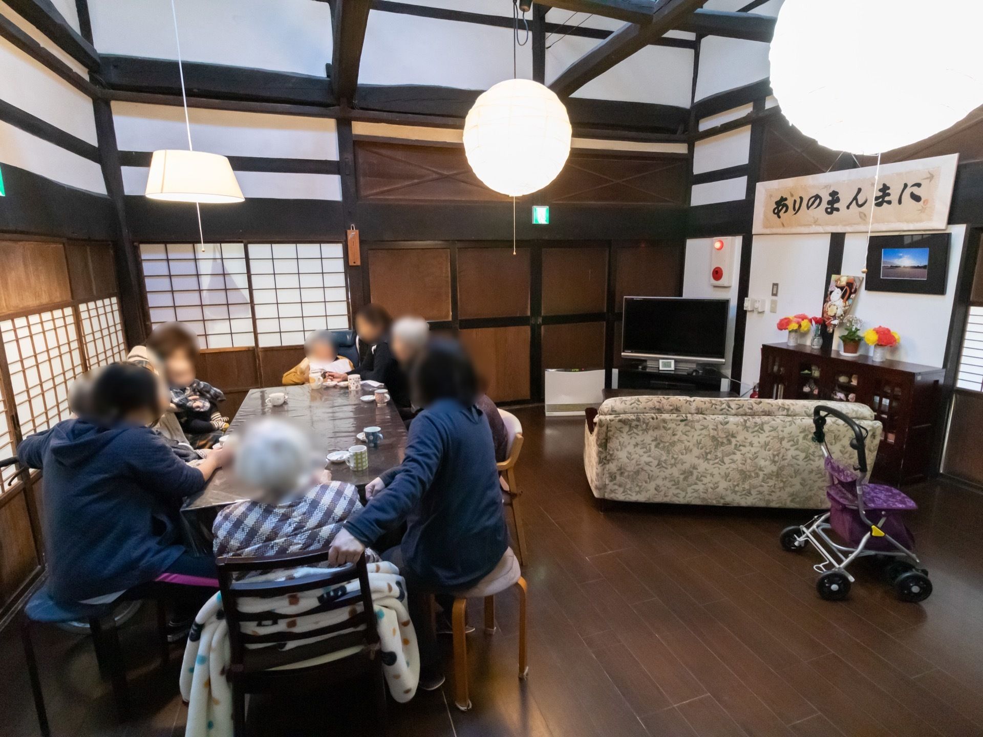 共有スペースに入居者様たちが集まりお茶を飲んでいる。床はシックなブラウンカラーのフローリングになっている。