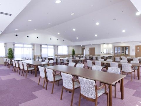 紫色のカーペットが敷かれ、テーブルと多くの椅子が並んでいる食堂
