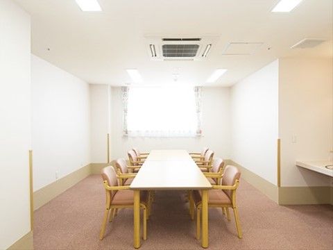 白色の天板の長テーブルの両側に合計８脚の椅子が置かれている談話スペース