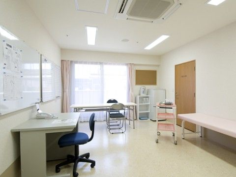 大きなドアは木目調になっている。窓にはレースのカーテンとピンクのカーテンが付いており、近くにはテーブルと折り畳みの椅子が置いてある。