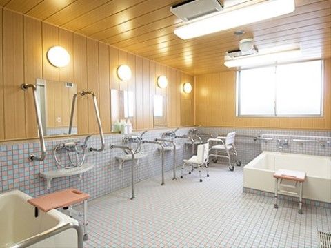 広い浴室には、シャワーチェアや手すりが備えてられてある。浴槽のふちには、浴槽への出入りをサポートする台が設置されている。