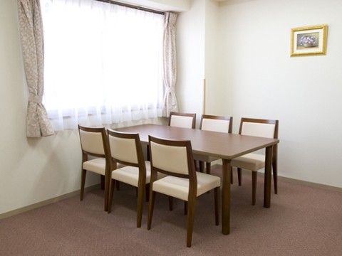 窓の近くにテーブルと６脚の椅子が置かれている談話スペース
