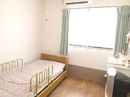 フローリングのシンプルな居室にはカーテンやベッド、ベッドが付いている。
