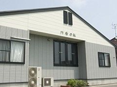 グレーと白の外壁に黒い屋根が付き、外壁にはホーム名が書かれている。