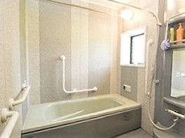 エル字型の手すりが設置された浴室には個浴槽やシャワーがある。