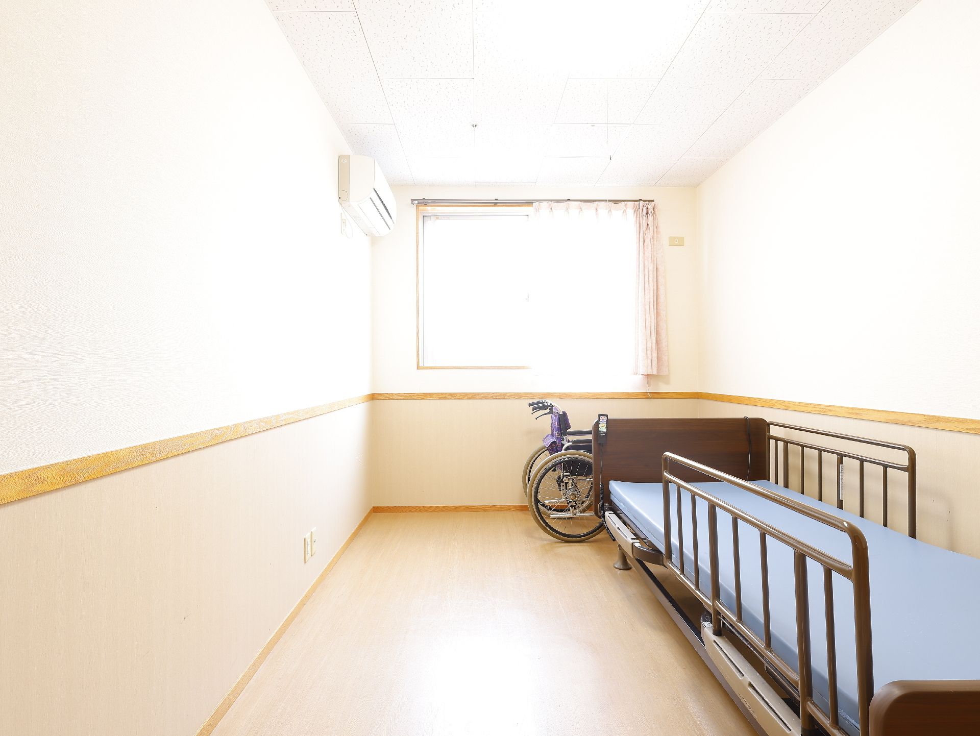 眼鏡をかけた車いすの高齢男性に高齢女性が寄り添い、二人で話ながら笑っている様子。