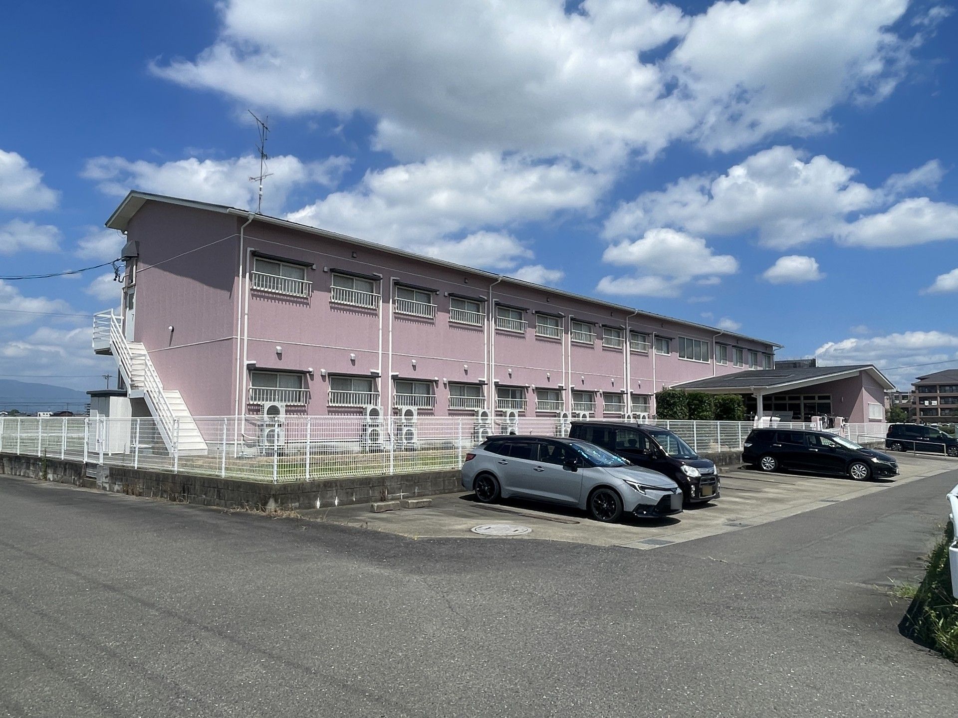 ピンク色の建物と駐車場