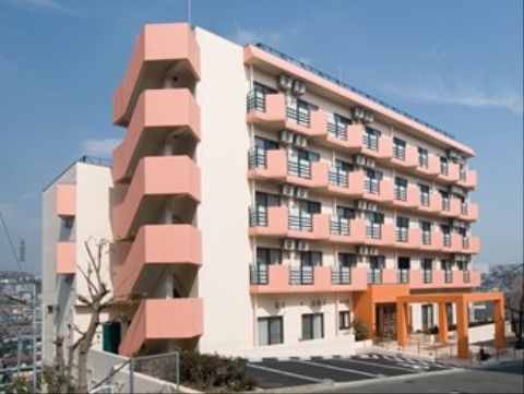 ピンク色の外壁が暖かみを感じさせる５階建ての施設外観