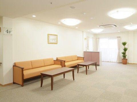 壁際に３人掛けのオレンジ色のソファが２台並べて置かれている休憩スペース