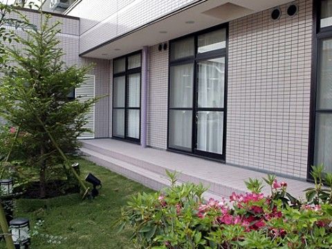 背の高い針葉樹の周囲に芝生や植栽があり、掃き出し窓から出ることができる庭園