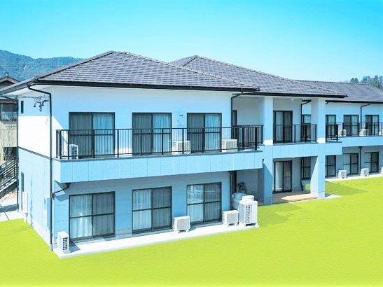 赤い屋根が印象的なグループホーム我家我家の外観。横に連なる連続した住宅のような外観写真
