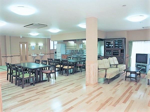 広い空間に複数人が座れるテーブルと椅子が並んでいる様子。施設内の共有スペース