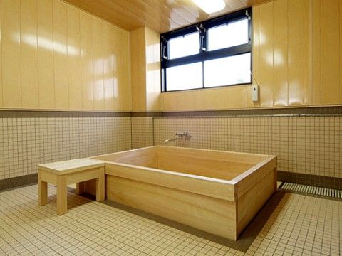 数人が同時に入ることのできる大きなヒノキの浴槽がある浴室。窓からは自然光が入り、リラックスできる空間になっている。