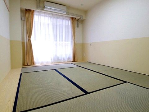 畳が敷かれた部屋になっており、エアコンが完備されている。畳の横は細い板間になっており、壁はベージュと白になっている。