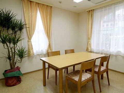 木目調のテーブルに椅子が用意されている。部屋はきれいで、隅には大きな観葉植物が置かれており、静かな雰囲気がある。