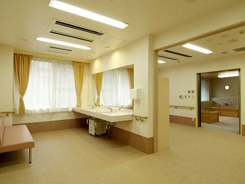 床はベージュ系のバリアフリーになっている。洗面台には大きな鏡が付いており、天井には細長い照明や空調設備もある。
