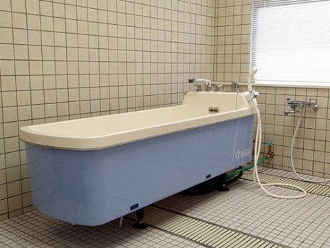 窓から光が入り込む明るい浴室になっている。縦長になった大きな介護浴槽が設置されており、壁にはシャワー付きの水栓が付いている。