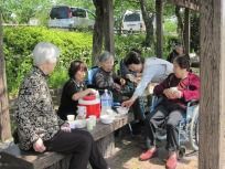 外に出てご飯を食べている様子の高齢者。スタッフと談笑している様子