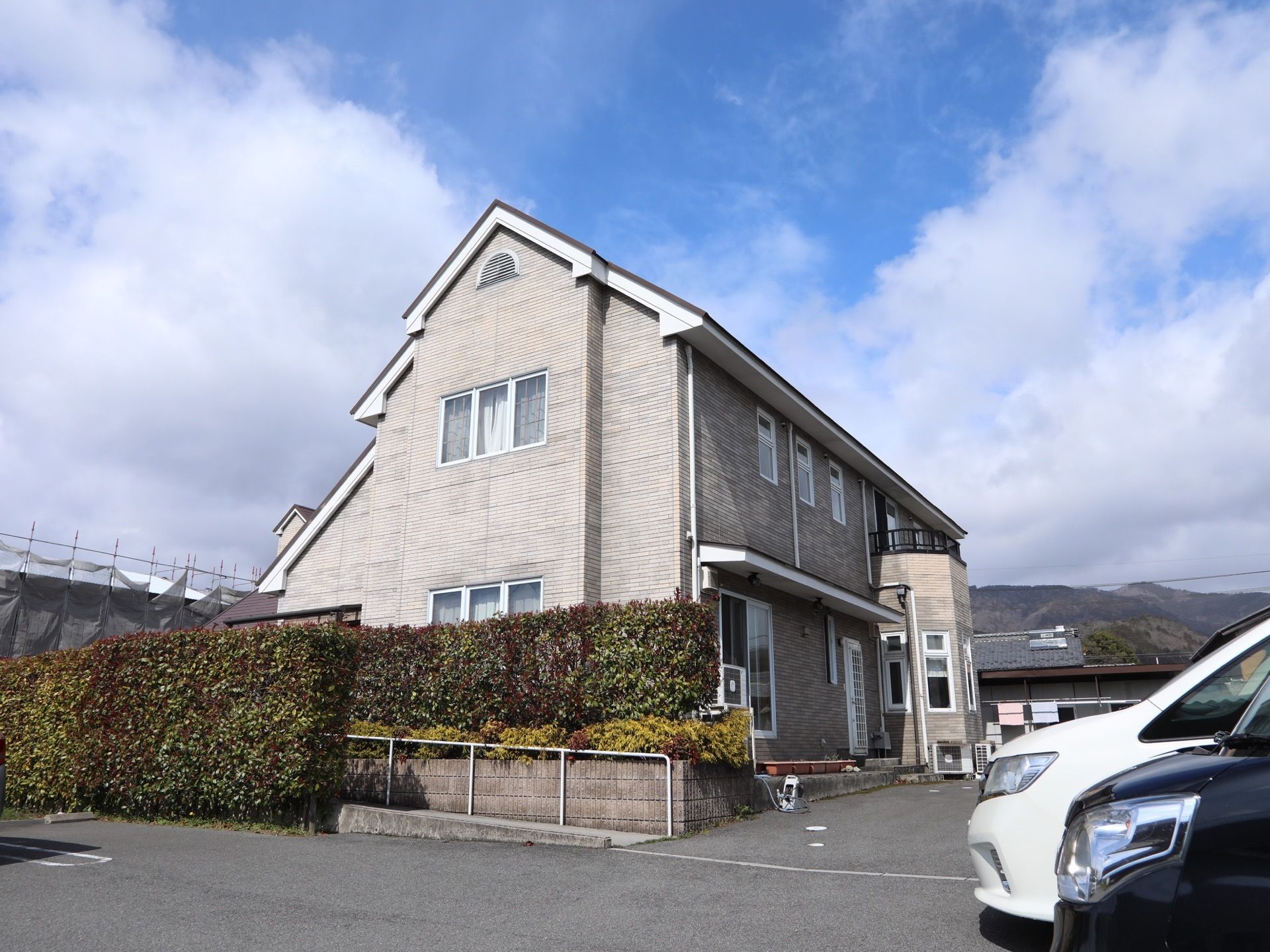 一軒家風のおしゃれな外観である。まわりの景観になじむ、落ち着いた色合いに施されている。敷地はアスファルトである。