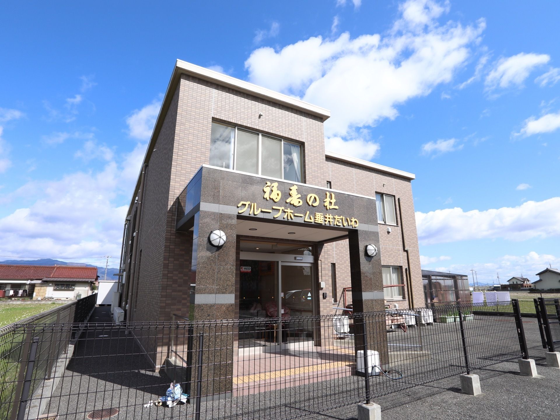 建物の外壁はブラウンで、入口部分は濃いブラウンである。入口の上には施設名が書かれていて目印となっている。