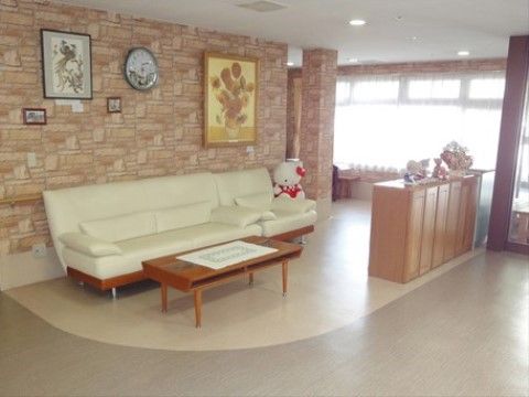 エントランスのホールには休憩スペースがある。床はベージュ色でアーチ状に仕切ることにより空間の分離がなされている。