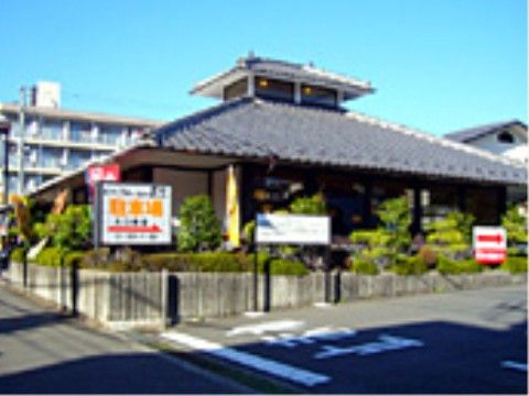 近所にある飲食店は、和風の建物となっている。入口には、駐車場へ案内する看板が建てられている。建物の周りには、植物が植えらている。