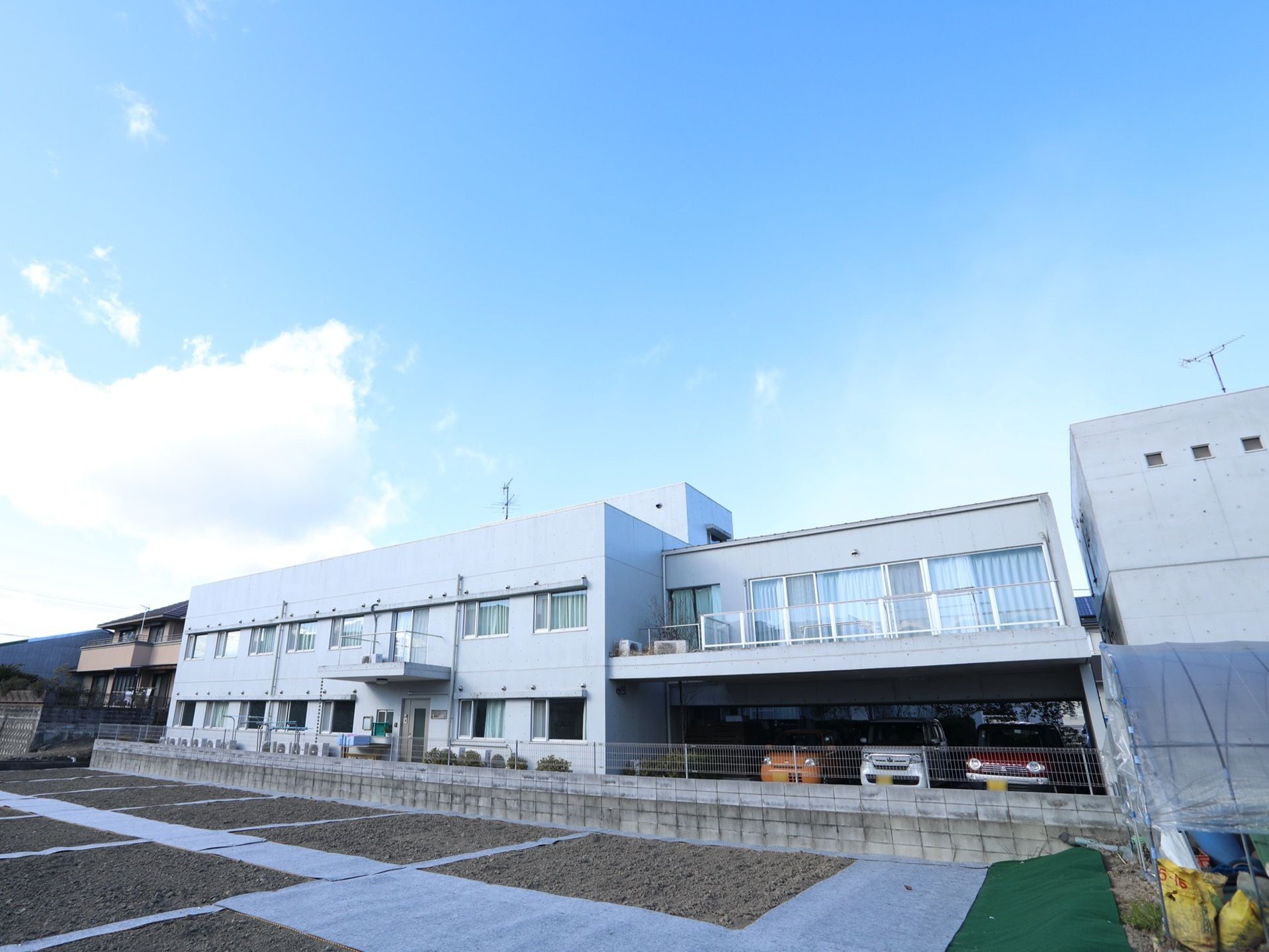 白壁の日照条件の良いところに建っている、２階建ての施設である。目の前には畑が広がり、のんびりとした暮らしができる。