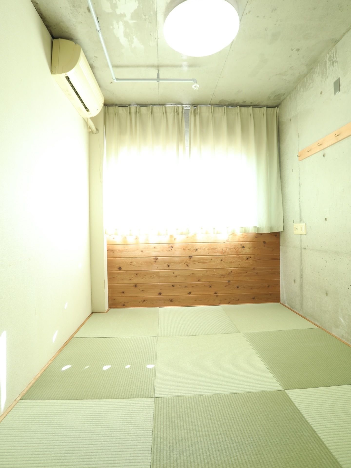 居室には大きな窓とカーテン、照明、エアコン、ハンガーフックが見られる。家具などは入居者様の使い慣れた物を持ち込んでいただける。