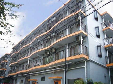 バルコニー下のオレンジ色の波打った形の幕板が印象的な施設外観