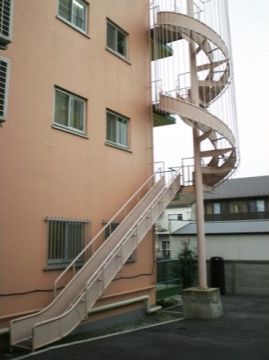 施設の外には非常階段が設置されている。２階までは螺旋階段になっており、２階から１階へは滑り台になっている。