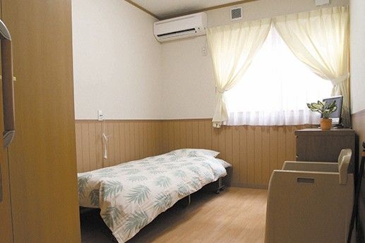 生け花に取り組んでいる高齢者とそれを補助するスタッフ。レクリエーションの一場面の写真