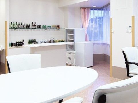 部屋の奥まったところにはL字型の窓があり、レースのカーテンとピンク色のカーテンが掛かっている。近くには1ドアの冷蔵庫もある。