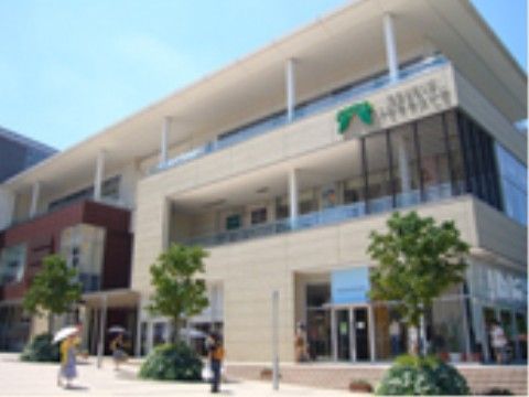 大型ショッピングセンターの外観である。3階建ての大きな建物の周りには木が植えられている。施設から3kmほどの離れたところにある。